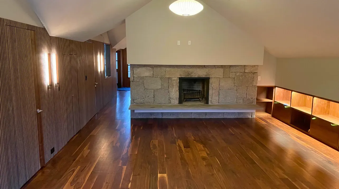 Dark refinished hardwood running the length of a panelled room